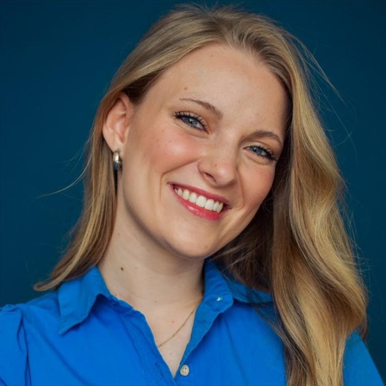 Paige McKenna headshot, bright smile, blue shirt on a navy backdrop