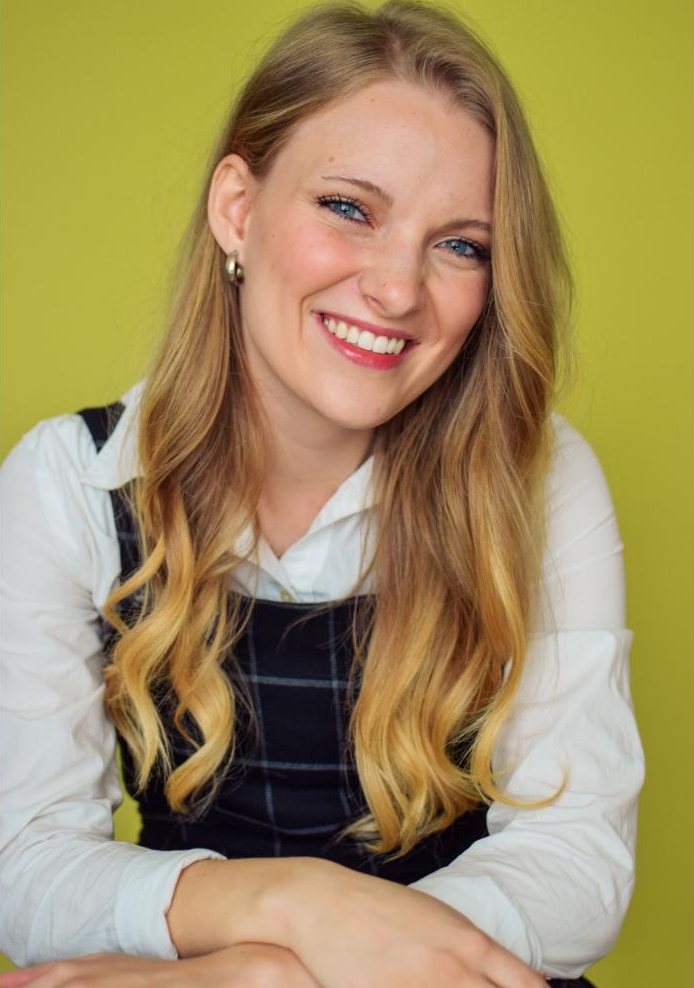 Headshot of Paige McKenna, smiling, long blonde hair, white collared shirt against a chartreuse backdrop